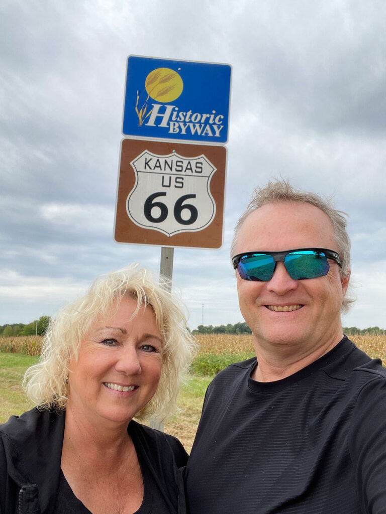 Selfie of professional photographers, Michael and Joannie Anderson, at a road sign marking Route 66.