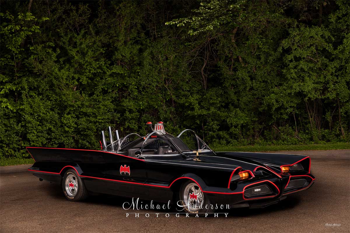 A cool light-painted photograph of the Batmobile on the street.
