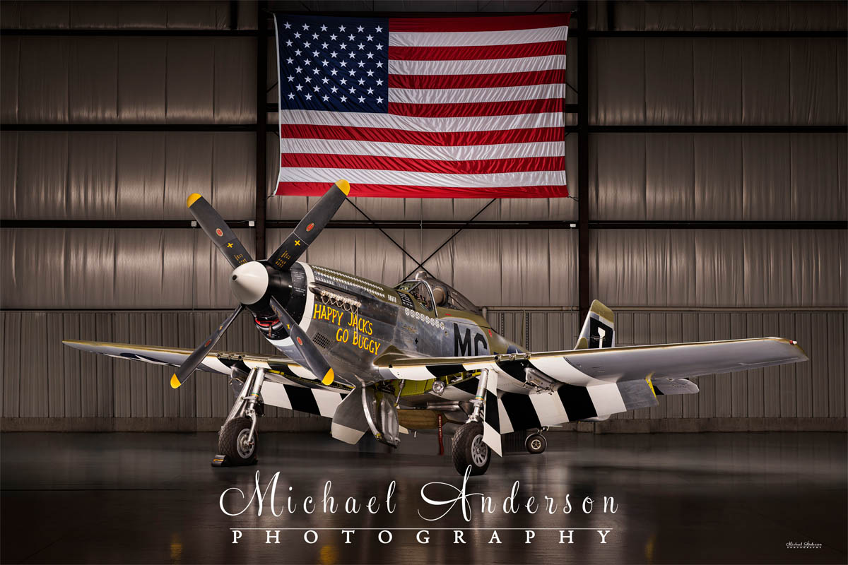 A cool light painted photograph of the P-51D Mustang, "Happy Jack's Go Buggy" in a hangar in Oshkosh, Wisconsin.