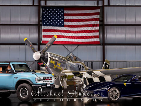 A wonderful light-painted photograph of three very unique vehicles. From left to right is a 2024 Ford Bronco Heritage Edition, the famous P-51 D Mustang “Happy Jack's Go Buggy”, and a 2025 Ferrari Roma Spider!