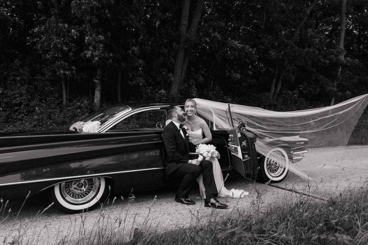 A cute couple pose with a stunning 1960 Buick Invicta on their wedding day.