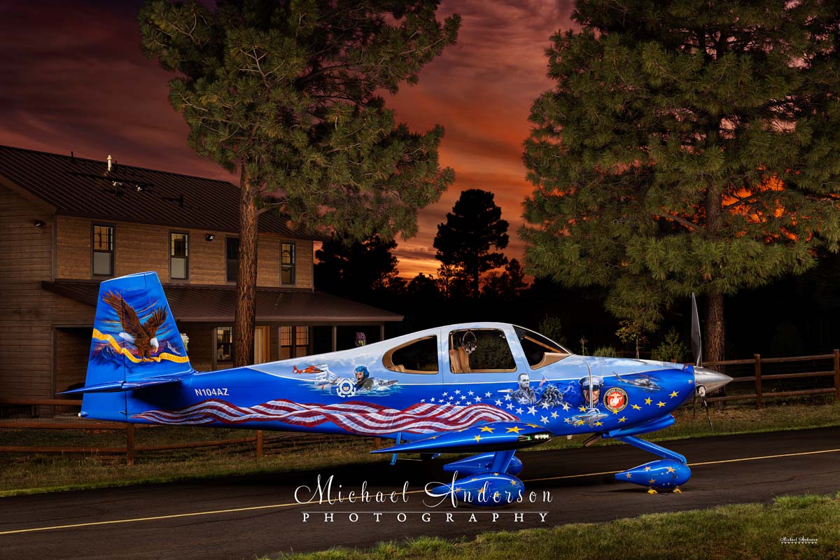 A pretty light-painted photograph of the Starboard side of Liberty N104AZ, as well as a cabin and the trees, at sunset.
